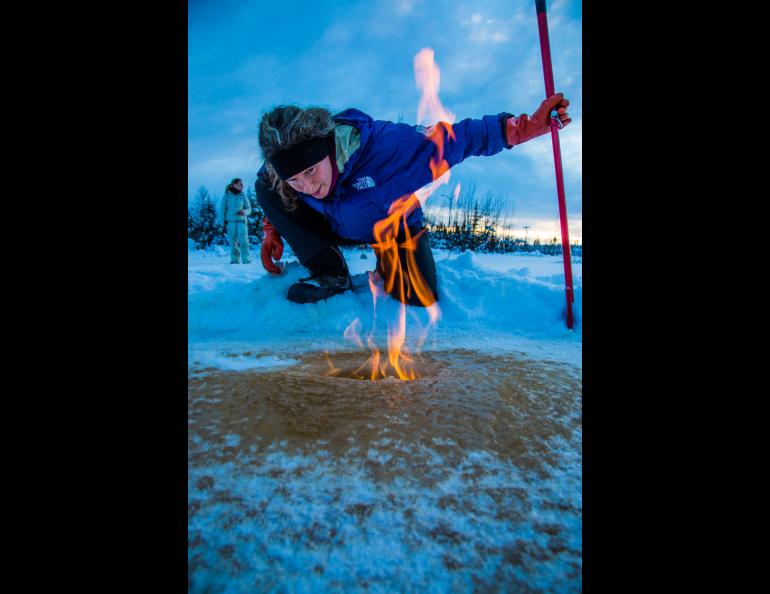 Katey Walter Anthony inspects flaming methane gas seeping from a hole in the ice on the surface of a pond on the UAF campus in February 2016. UAF photo by Todd Paris.
