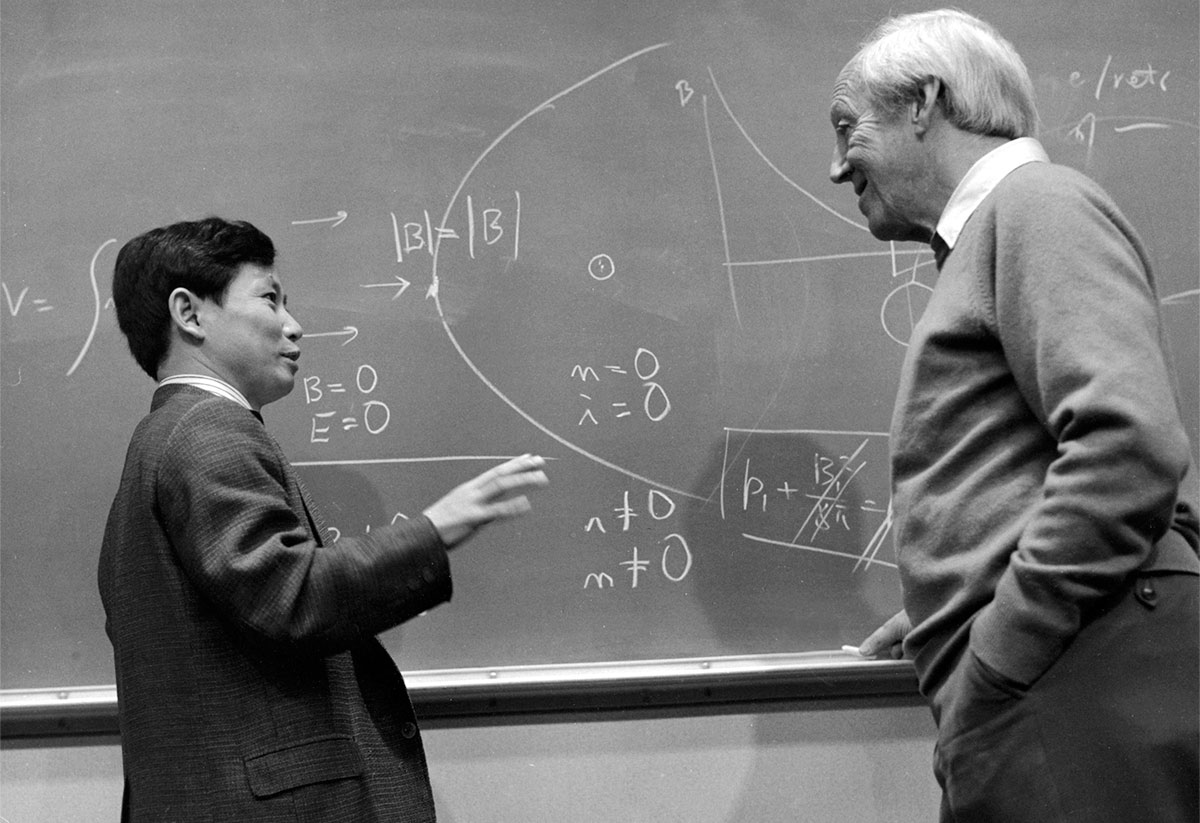 Akasofu next to a chalk board speaking to another man. 
