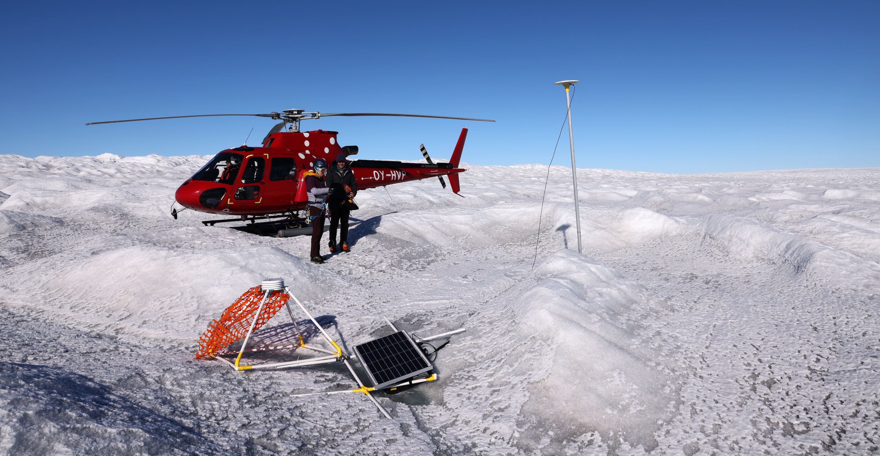 Two people on ice outside of a helicopter