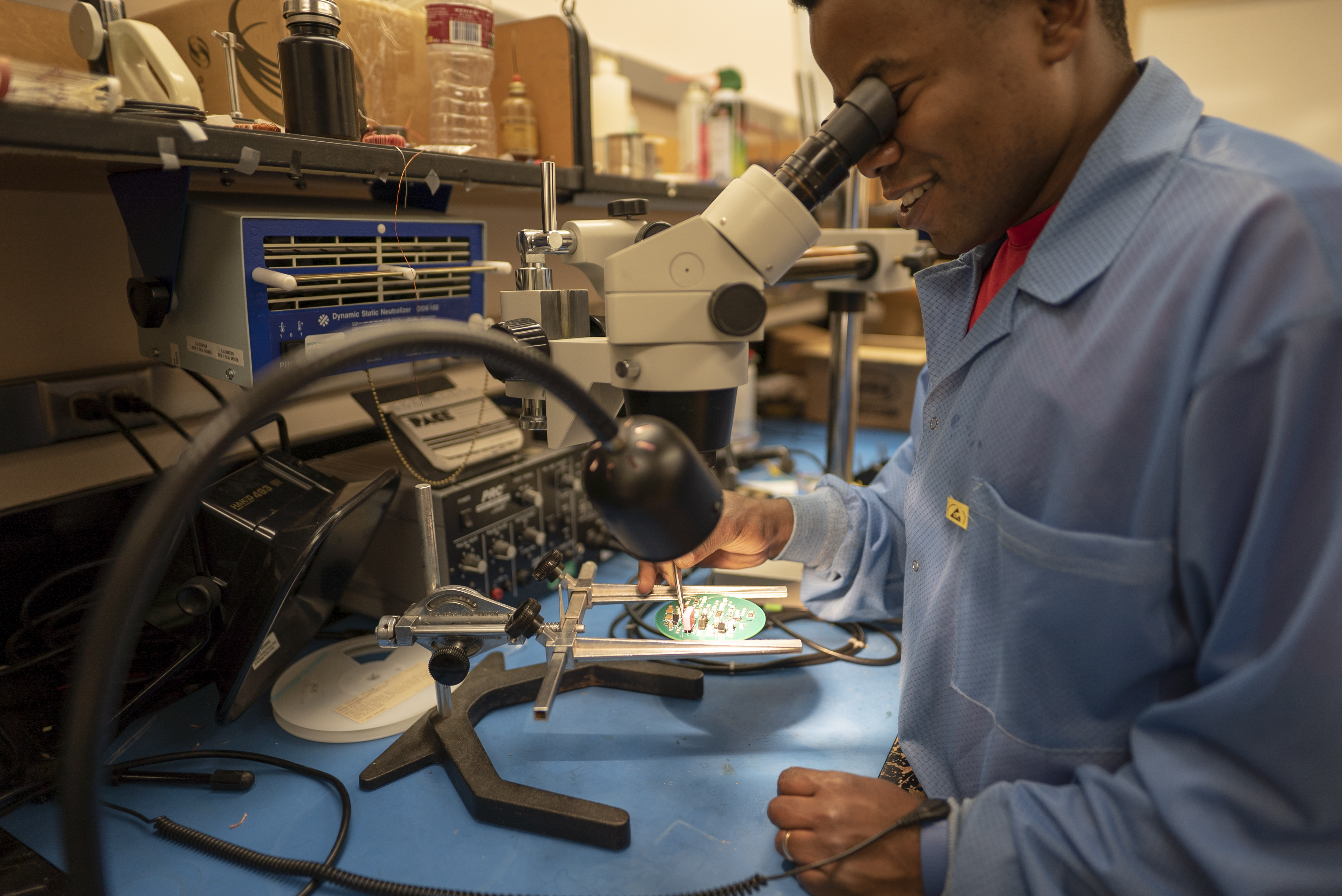 Man look through microscope working with hardware. 