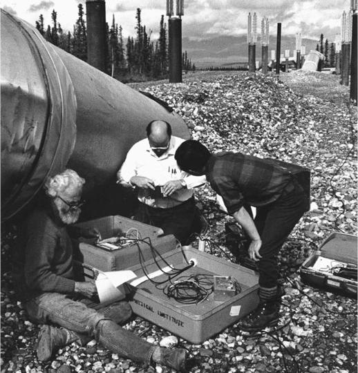 Researchers with instruments and a piece of the pipeline