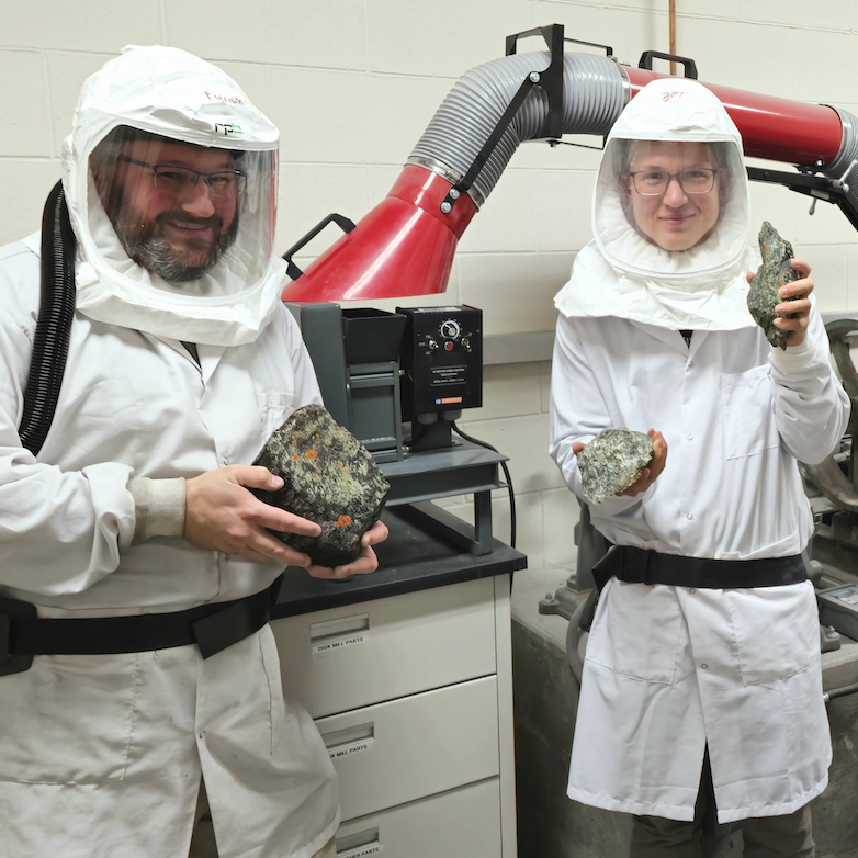 Dr. Hofmann and Lee in full PPE for rock crushing in the Geochronology Lab. They are holding Livengood serpentinite samples. (Courtesy of Lee Aeo)