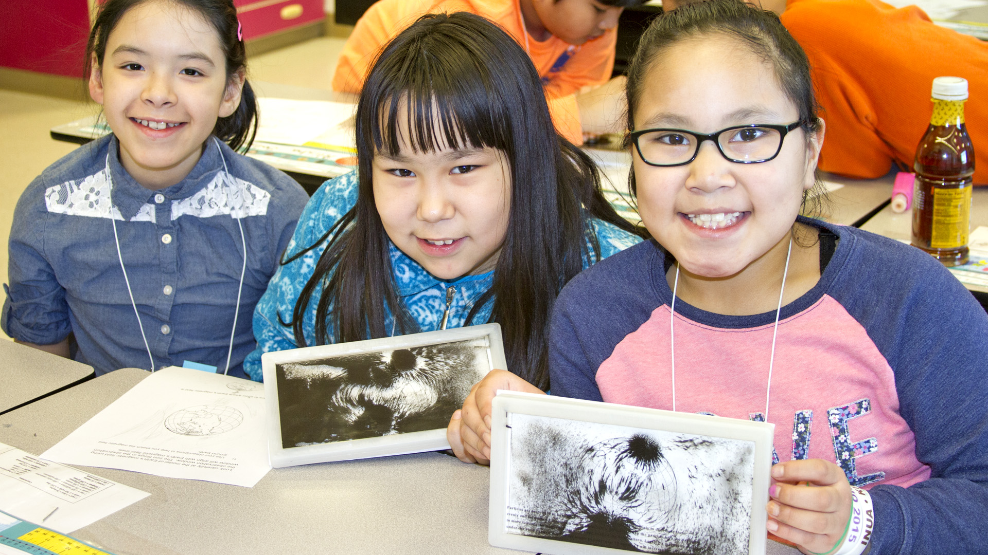 3 Girls holding iron filings in a classroom. 