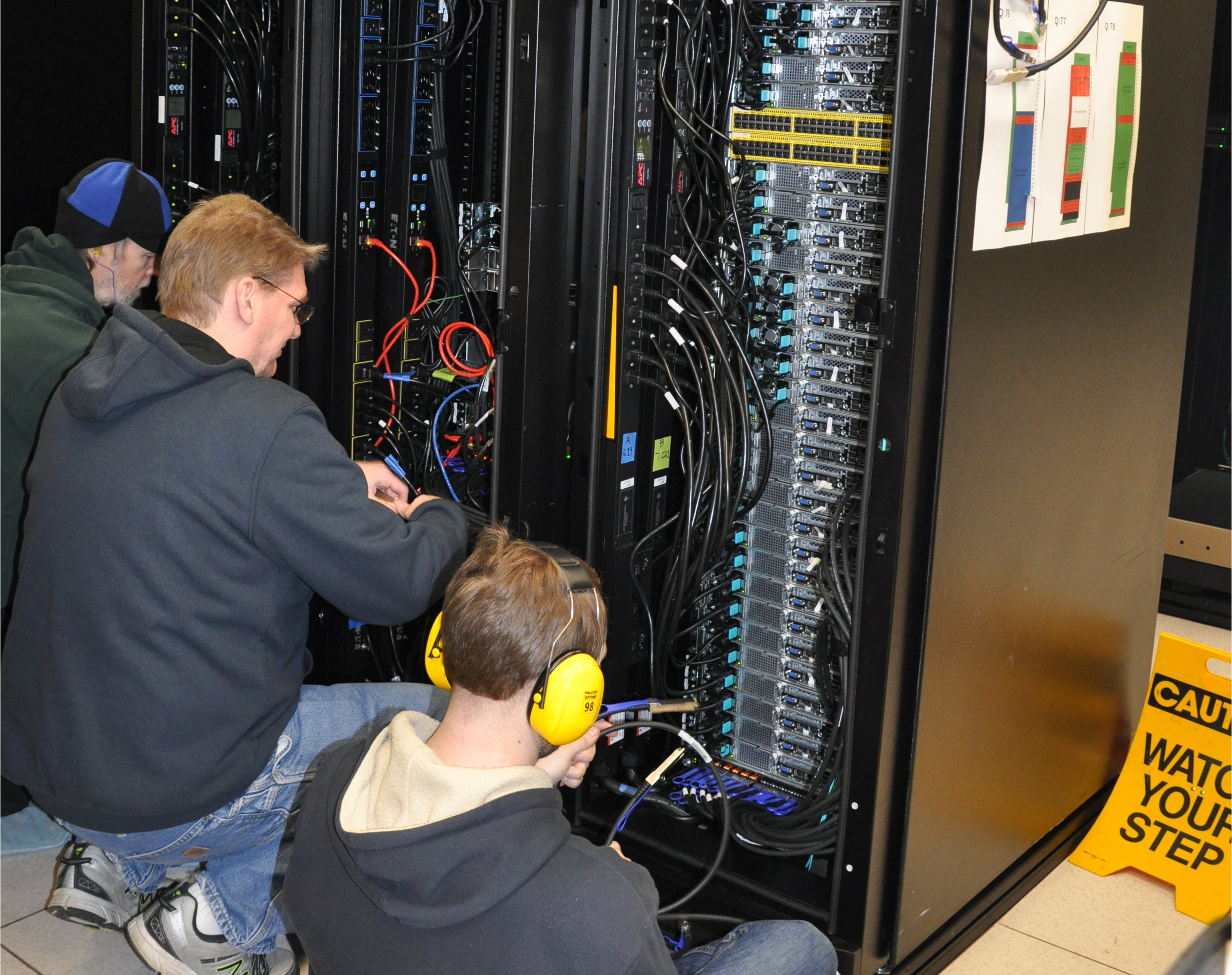 Three people working with computer hardware