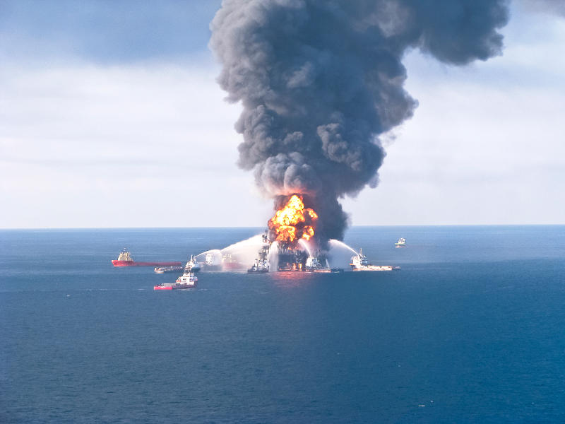 Deepwater Horizon oil rig on fire, with boats surrounding it hosing water to put it out