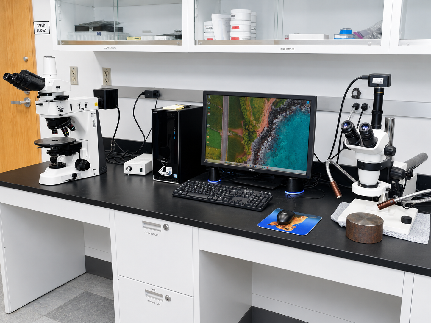 Two microscopes with a desktop pc between them.