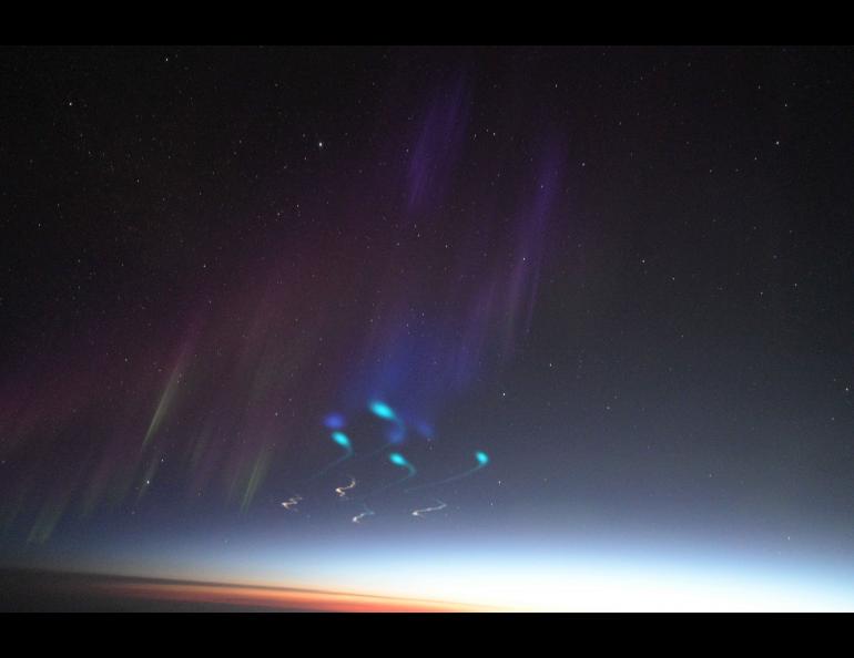 Clouds of vapor traces caused by chemical releases from the rocket form a grid pattern to show the movement of the wind in the upper atmosphere. The photograph was made from a NASA aircraft off the northeast coast of Greenland. Photo by Jason Ahrns
