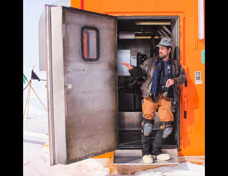 Dale Pomraning stands in the doorway of BOB — the Big Orange Box — at Windless Bight. BOB is a former walk-in freezer with foot-thick walls. It houses computers and provides solar and diesel-fired generator power to nearby infrasound sensors that help detect nuclear detonations. Pomraning wears knee