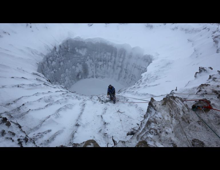 A member of an expedition group stands on the edge of a newly formed crater on the Yamal Peninsula in northern Siberia in November 2014. Photo by Vladimir Pushkarev, Reuters via Nova