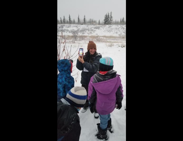 Dana Brown, an ecologist at the UAF International Arctic Research Center, teaches students in Venetie, Alaska, how to make ground-based observations of river ice using NASA's GLOBE Observer App. The ground observations were used alongside the drone observations to interpret the data from multiple pe