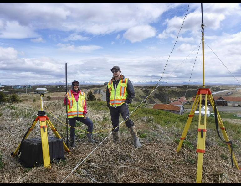 Graduate students, from left, Roberta Glenn and Reyce Bogardus stand next to their kinematic GPS instruments while surveying in June 2021 in Pilot Point. UAF/GI photo by Chris Maio.