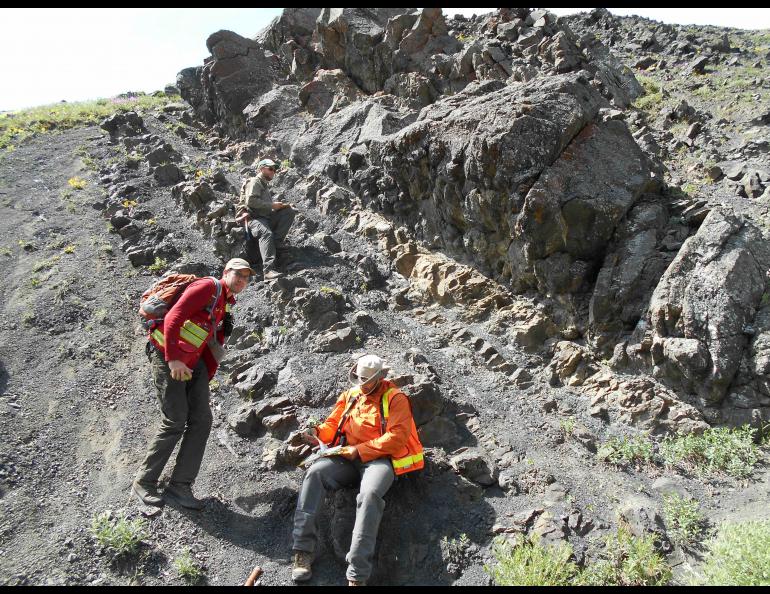 Sedimentary rocks of the Cantwell Formation, representing a prehistoric floodplain environment, are shown in this June 2017 photograph. Dinosaur tracks are visible at the base of the thick, upper sandstone bed. Photo by Paul McCarthy