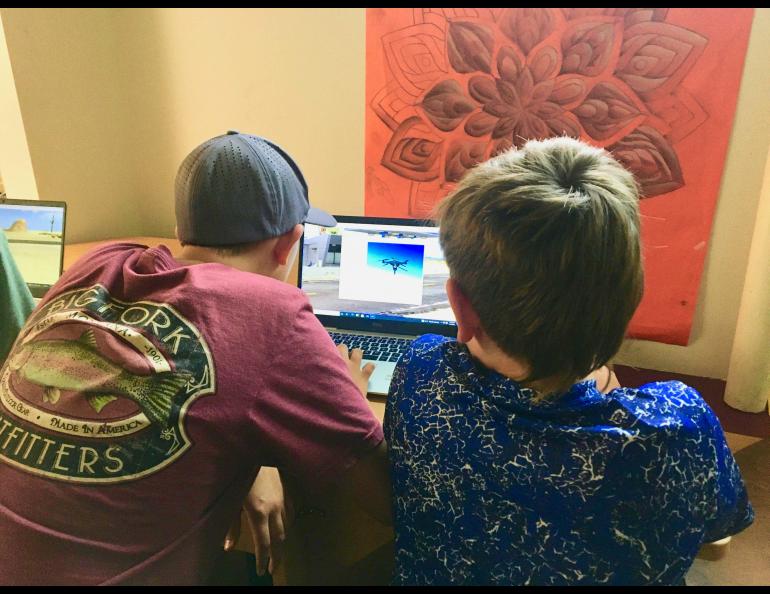 Two Delta Junction students use the drone flight simulator that Nick Adkins brings on his education outreach trips. Photo by Rod Boyce