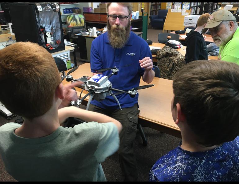 Nick Adkins explains the parts of a drone and its flight capabilities to Delta Junction students. School librarian Norm Cosgrove, who teaches the weeklong summer school drones class, listens. Photo by Rod Boyce