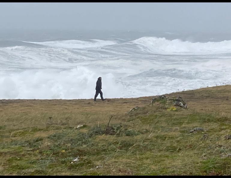 Filmmaker Fritz Mueller walks at the edge of St. Paul Island as waves crash ashore, driven by the remnants of Typhoon Merbok as it passes over St. Paul Island. Photo by Chris Maio