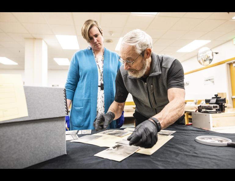 Rasmuson Library archivist Rachel Cohen and professor Matthew Sturm look at Sourdough Expedition photographs that Sturm unexpectedly found during unrelated research. UAF/GI photo by JR Ancheta.