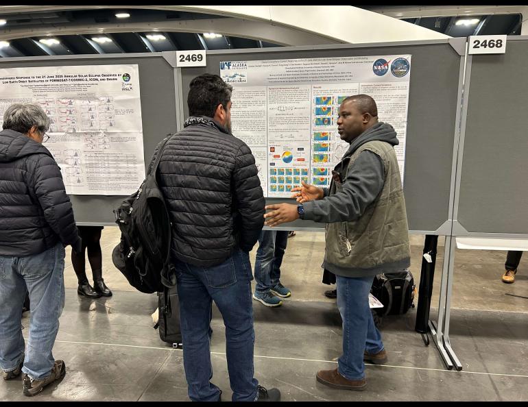 UAF Geophysical Institute postdoctoral fellow Charles Owolabi, at right, shows his work. Owolabi is a space physicist. Photo by Rod Boyce.