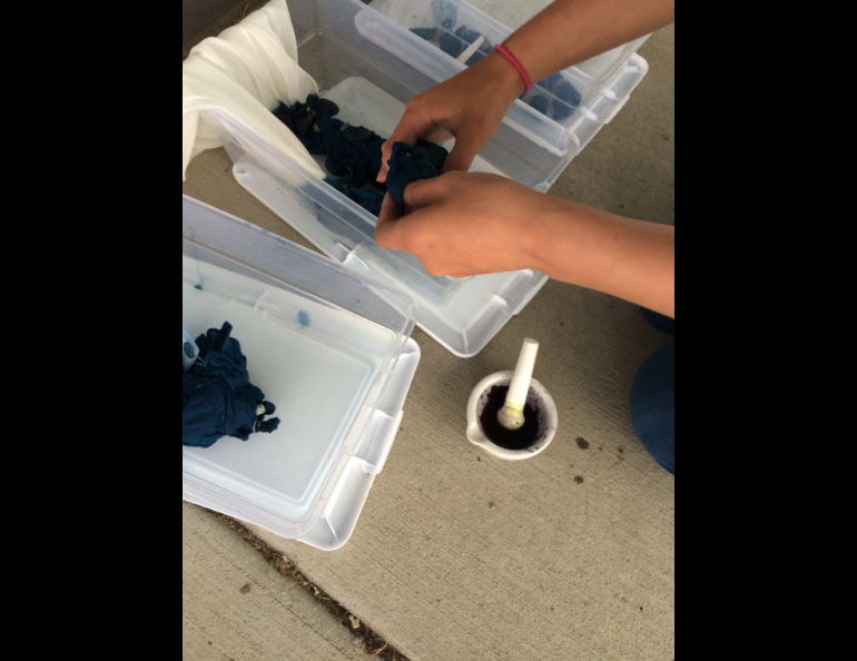 A summer camp participant uses local flower pigments and natural indigo to create dye patterns on a silk scarf. Photo by Perrin Teal Sullivan
