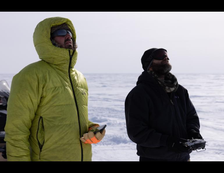 UAF postdoctoral fellow Achille Capelli, left, and drone pilot Matthew Westhoff of the Alaska Center for Unmanned Aircraft Systems Integration at the UAF Geophysical Institute watch the drone in flight. Photo by Bryan Whitten