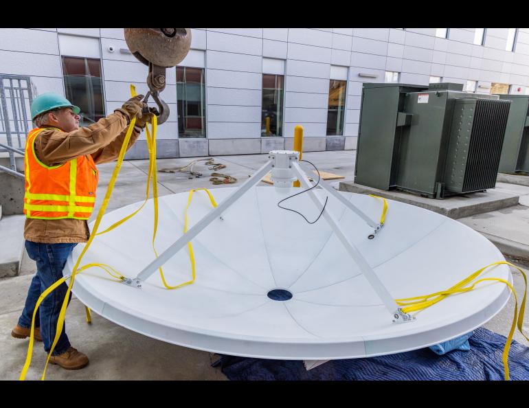 Ron Ashcraft from Cygnet Construction secures the antenna dish for the lift. The Geographic Information Network of Alaska (GINA) and UAF Facility Services install a brand new antenna on the roof of the Usibelli Engineering building on Saturday, April 6, 2024. UAF photo by Marina Barbosa Santos