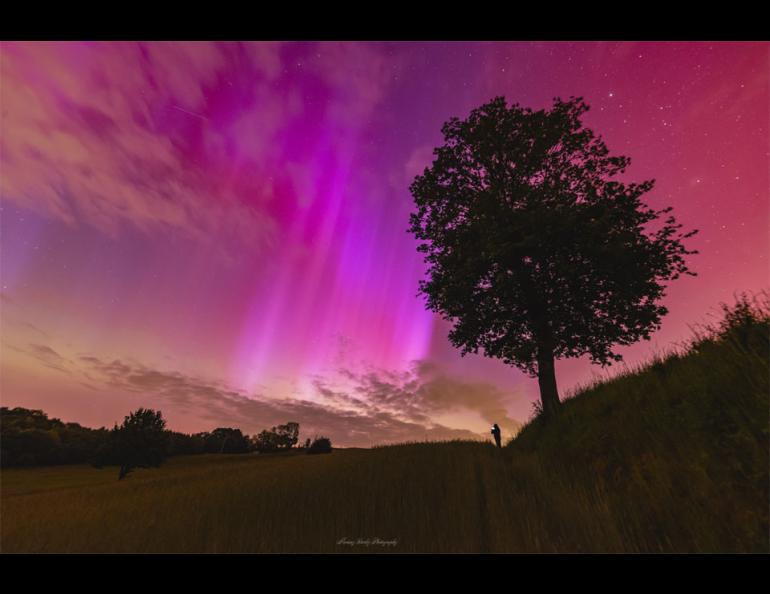 A red and rayed aurora was captured in a single 6-second exposure from Racibórz, Poland, May 10, 2024. The photographer's friend, seeing an aurora for the first time, is visible in the distance also taking images of the beautifully colorful nighttime sky. Photo by Mariusz Durlej via NASA APOD