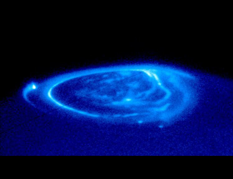 A close-up of Jupiter’s aurora shows auroral footprints of three moons: Io (along the left-hand limb), Ganymede (near the center) and Europa (just below and to the right of Ganymede's footprint). These emissions flow on Jupiter's magnetic field. NASA image, John Clarke (University of Michigan)