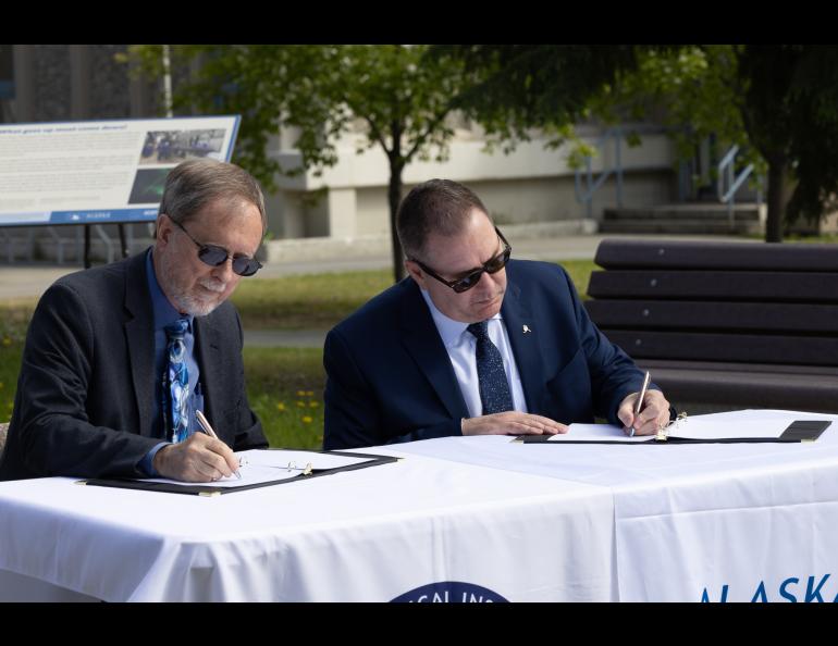 UAF Geophysical Institute Director Bob McCoy and Alaska Aerospace Corp. CEO John Oberst sign a memorandum of understanding in front of the GI building on Thursday, June 10, 2025. UAF/GI photo by Bryan Whitten: