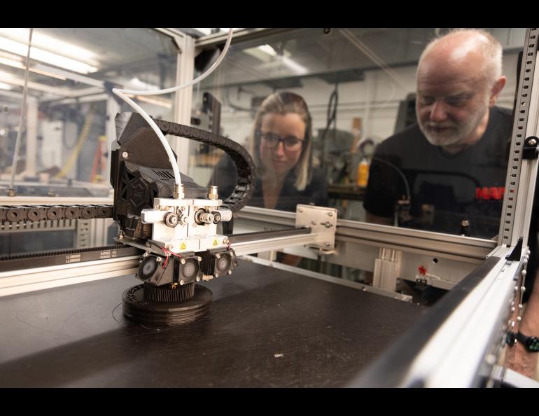 Kylee Branning and Mark Conde watch a part being 3D-printed in the UAF Geophysical Institute machine shop. UAF/GI photo by Bryan Whitten