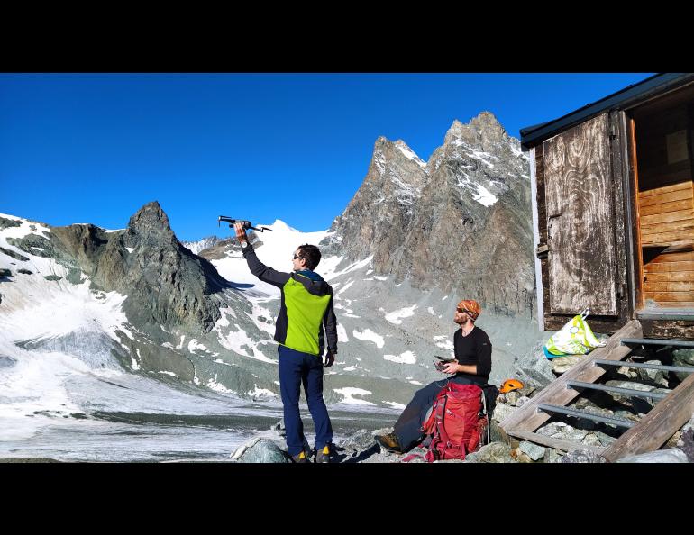 Pascal Buri, left, holds a drone ready for flying in the Swiss Alps in August 2021 for the study of how mountain glaciers interact with the atmosphere. Thomas Shaw of the Institute of Science and Technology Austria prepares to pilot the drone. Photo courtesy of Pascal Buri