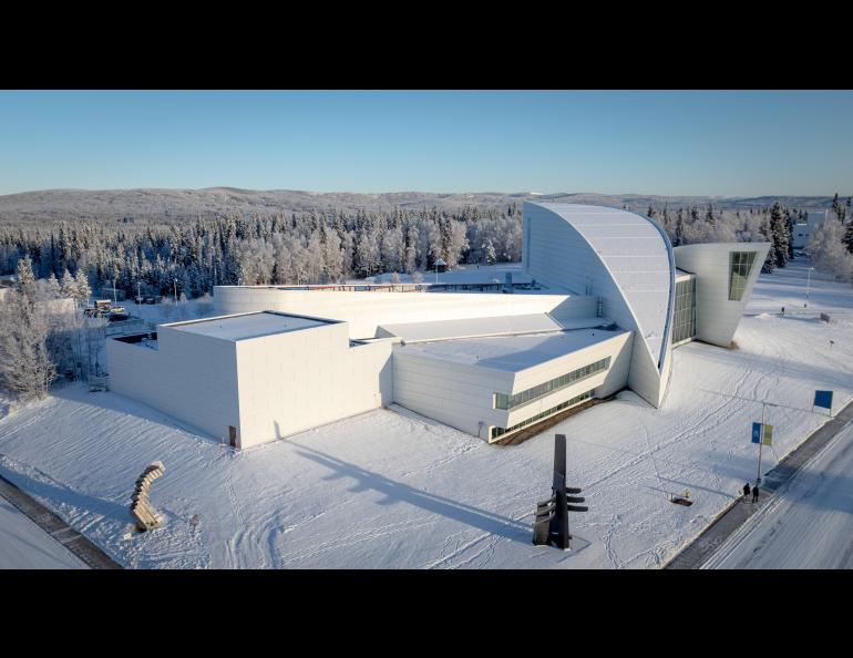 Aerial view of the new planetarium shows a white, modern complex surrounded by snow-covered forest and hills under clear winter light. The image, taken in November 2025, shows the planetarium addition to the west side of the UA Museum of the North. The square planetarium addition is at left.