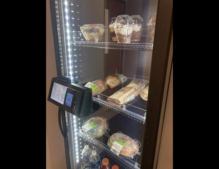 A view through the class door of a refrigerated machine with food items inside.