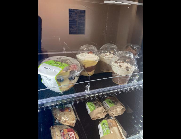 A view through the class door of a refrigerated machine with food items inside.
