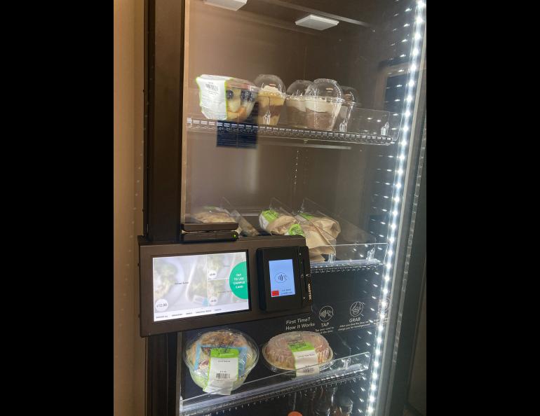 A view through the class door of a refrigerated machine with food items inside.