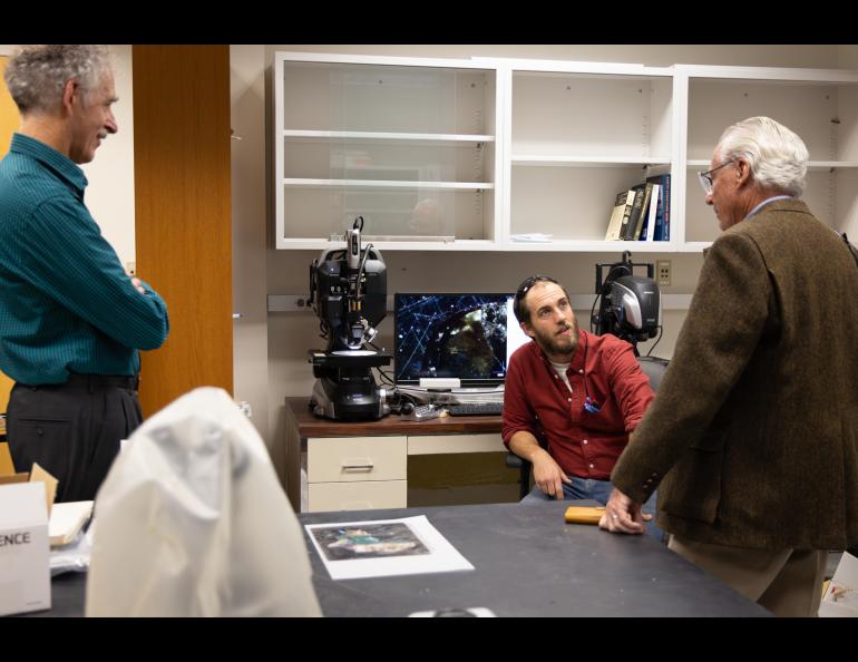Geochronology Lab Director Sean Regan, center, answers questions on a tour of UAF laboratories. The Keyence microscope system with laser-induced breakdown spectroscopy capabilities is pictured, with a microscope image of a meteorite sample on the adjacent screen. UAF/GI photo by Courtney Holtzclaw