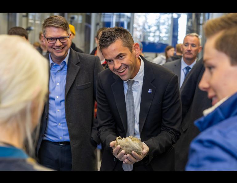 Two men look delighted while one of them holds a hibernating Arctic ground squirrel in his hands