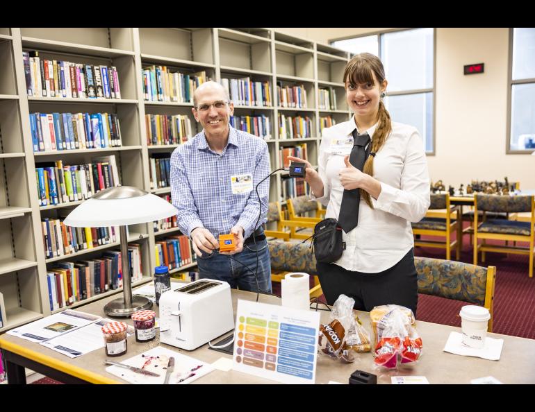Bill Simpson and Meeta Cesler-Maloney hold up a couple of air sensors while making toast at the 2023 Arctic Research Open House. UAF/GI photo by JR Ancheta.