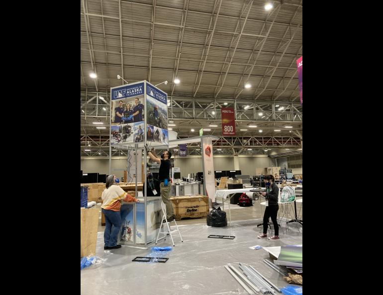 A step stool is the tallest ladder the booth assemblers can use without hiring a contractor. Lifting the upper part of the tower into place is a tricky and delicate maneuver. Photo by Kelly Eagan