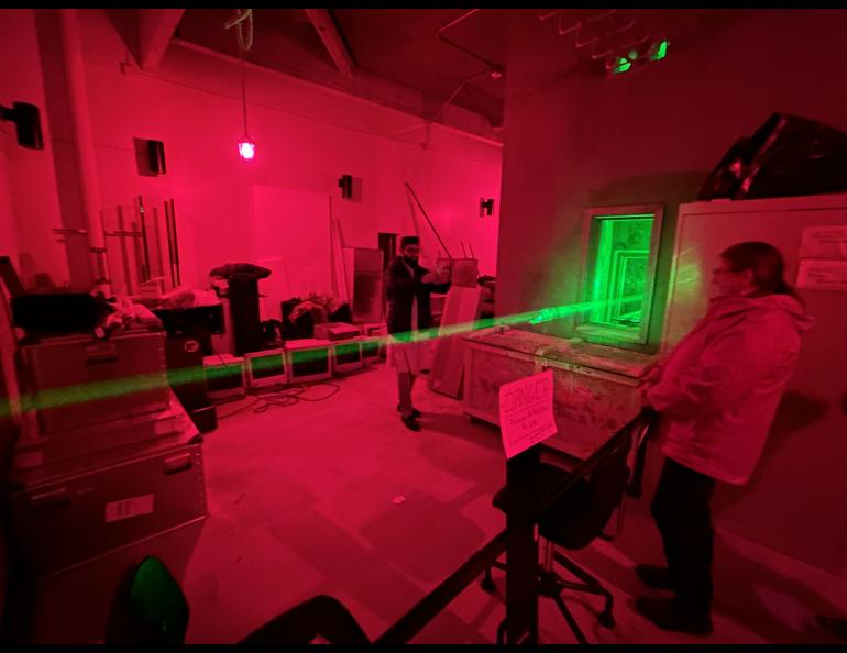 Julie Striker, right, and Md. Eyaqub Hussein on the other side of the beam, observe the Big Green Beam at the Lidar Research Laboratory during the Poker Potluck Pig Roast on Aug. 23, 2024. Photo by Rod Boyce