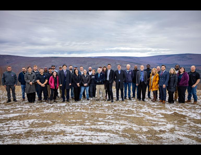 A large group of people line up and smile at the camera on a ridge above Poker Flat Research Range launchpads