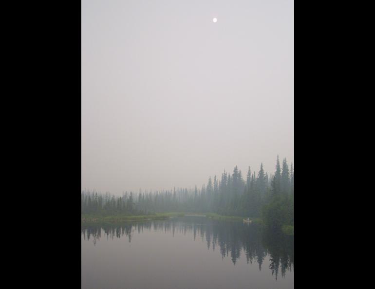 Fire smoke obscures the view of a canoeist and the sun in July 2004. Photo by Ned Rozell.