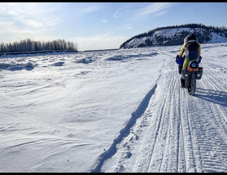 Forest Wagner rides his fat bike near Bishop Rock, right, a pinch point on the flow of the Yukon River, on April 5, 2026. Photo by Ned Rozell.