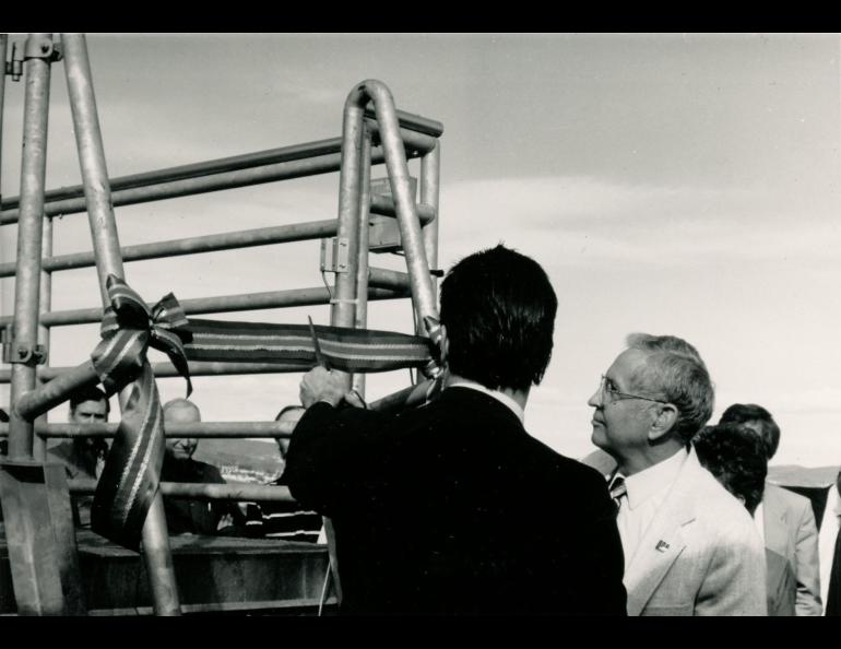 Black and white photo of people cutting a ribbon