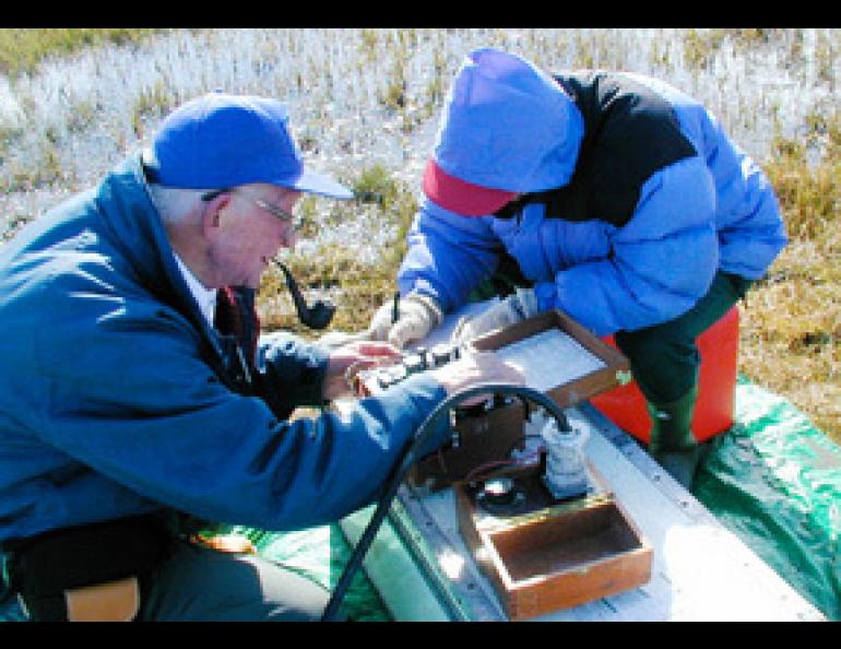Max Brewer takes a permafrost measurement at a site near Barrow he established more than 50 years ago. With Brewer is graduate student Huijun Jin. Photo by Kenji Yoshikawa.