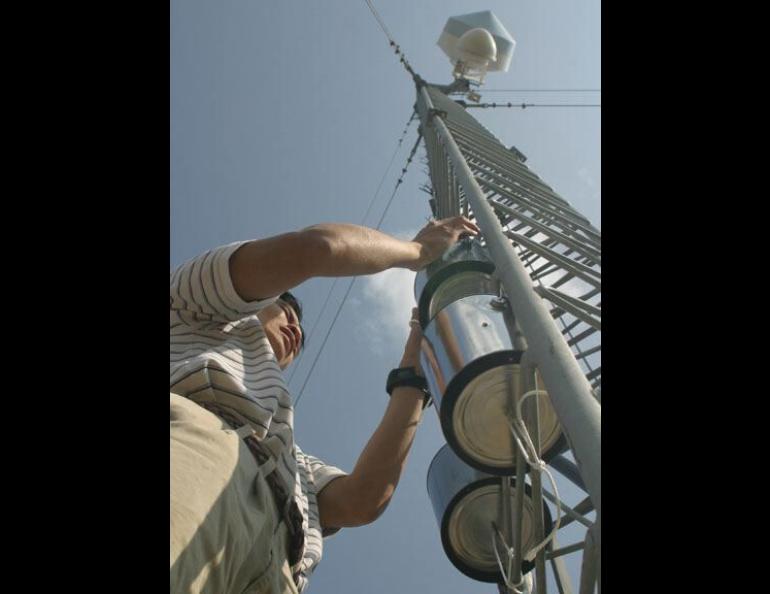  Photo: Ted Wu, an environmental toxicologist studying at the University of Alaska Fairbanks, hangs a device to capture pollutants in Alaska air at Poker Flat Research Range north of Fairbanks. Ned Rozell photo. 