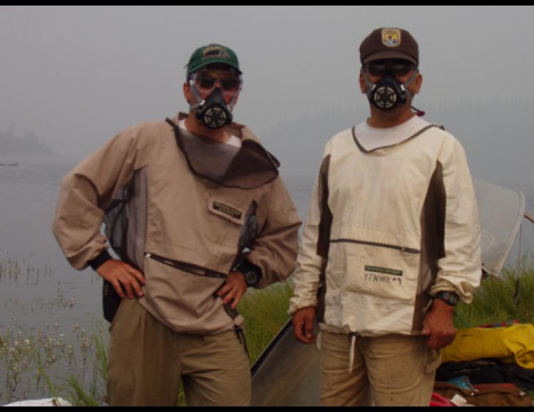 U.S. Fish and Wildlife Service biologists Mark Bertram, left, and Jim Akaran wear respirators while working at Burman Lake in Yukon Flats National Wildlife Refuge. Thick smoke in Fairbanks extended their work trip at the lake to nearly double its scheduled time. Photo courtesy of Mark Bertram, U.S. Fish and Wildlife Service.