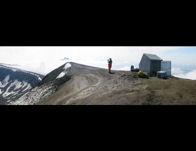 The gray fiberglass hut in which the Alaska Volcano Observatory’s Guy Tytgat spent a miserable night on Okmok Caldera. Here, in better weather, Jackie Caplan-Auerbach is pictured in 2002. Photo by Guy Tytgat.
