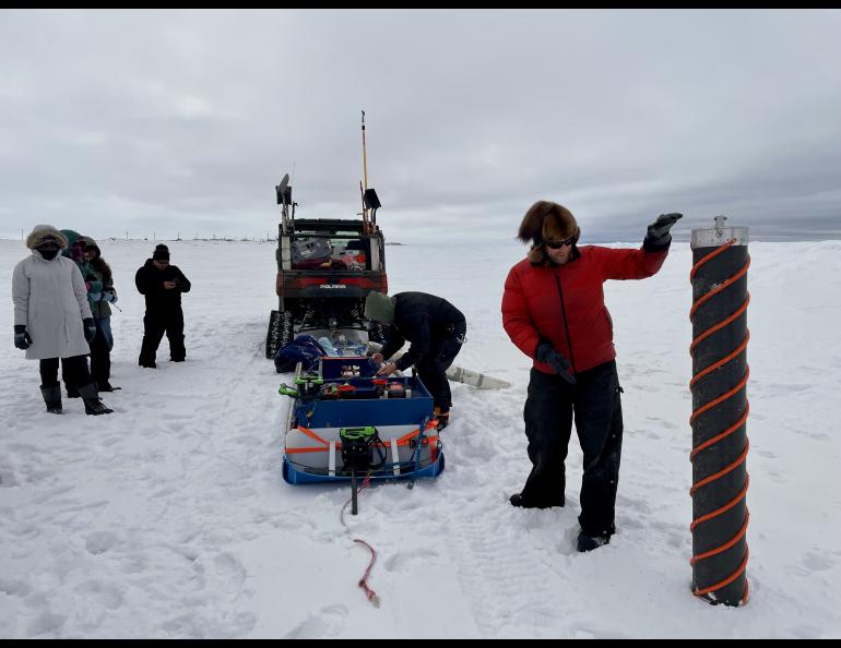 Ice auger and sled on ice with people