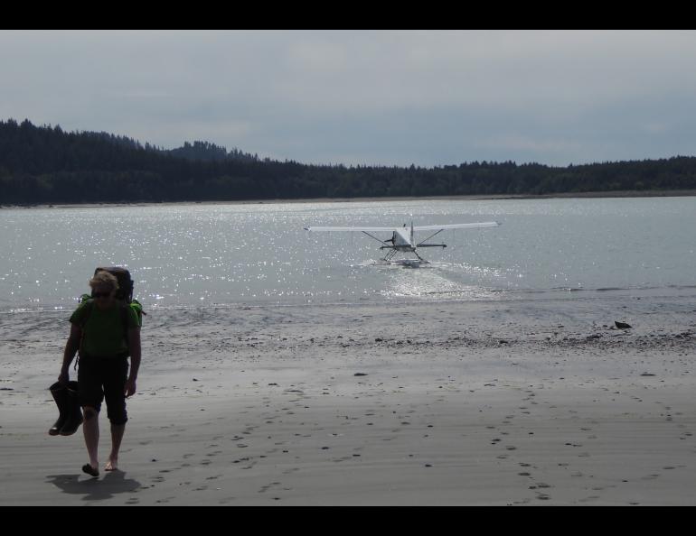 Dan Mann walks from a float plane in Anchorage Cove of Lituya Bay in Southeast Alaska. The pilot had just dropped him off for a 12-day trip. Photo by Ned Rozell.
