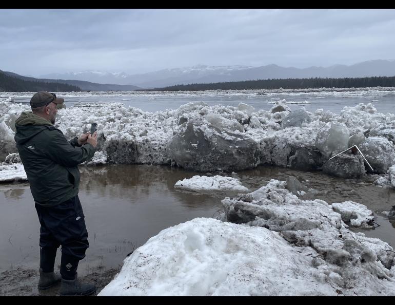 Ryan Becker, a teacher at the Eagle school, takes a photo of the toppled Front/Lincoln Street sign after Yukon River ice overtopped the town’s seawall on the morning of May 13, 2023. Photo by Ned Rozell.