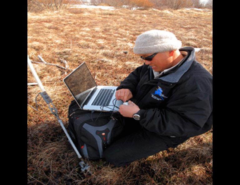 UAF permafrost researcher Kenji Yoshikawa downloads temperature data from his permafrost observatory in Koliganek. Photo by Ned Rozell.